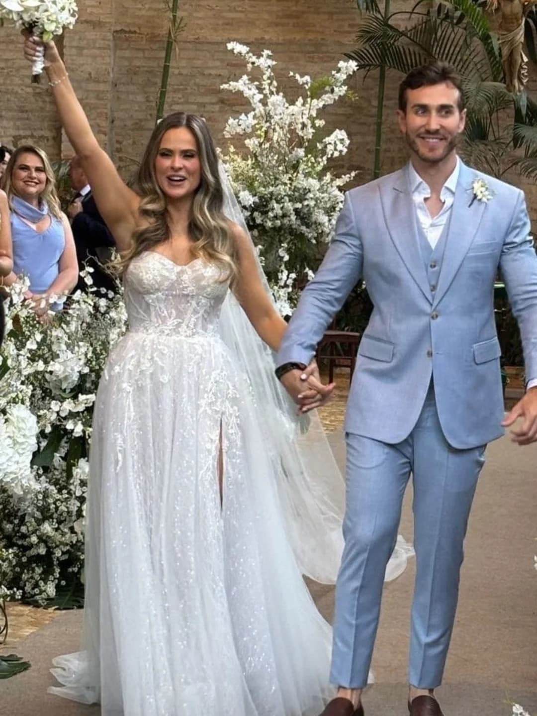 Casal comemorando, noivo em terno azul-claro